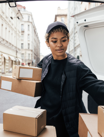 Delivery worker unloading cardboard boxes while standing at van